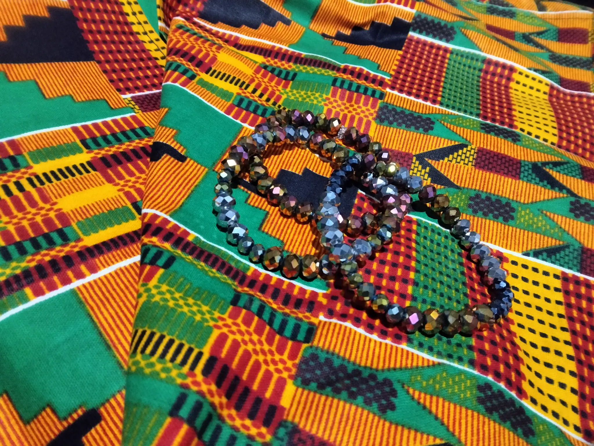 MO iridescent crystal glass rondelle bracelets with blue, purple and gold-toned reflections on Ghanaian-print fabric
